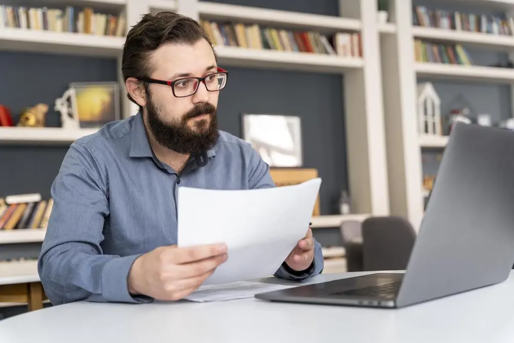 An adult reading a health reimbursement document at a kitchen table