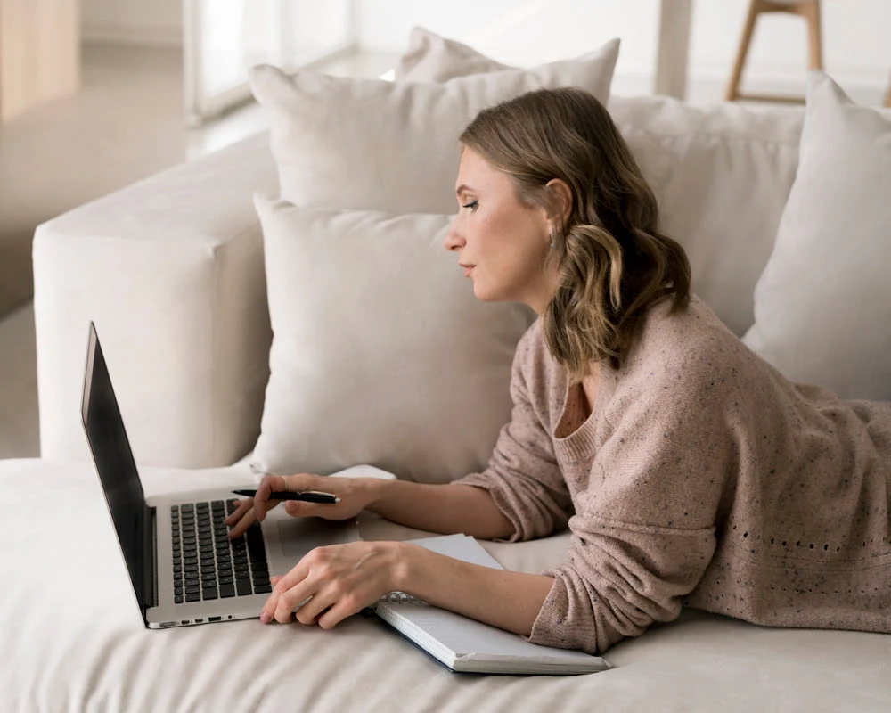 A person using a laptop while reviewing documents at home